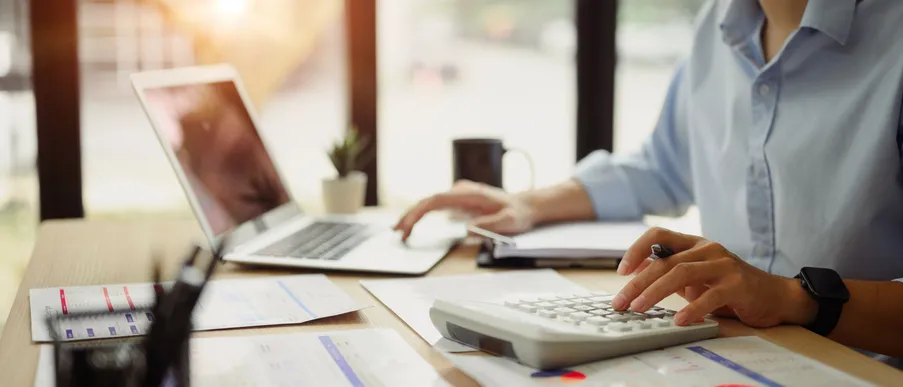 Accountant working through financial reports with a calculator at a desk
