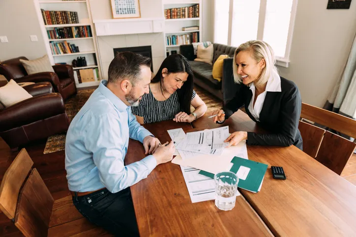 Financial advisor reviewing documents with two clients at a dining room table
