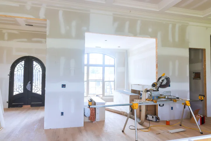 Home interior mid-remodel with fresh drywall and a miter saw work station