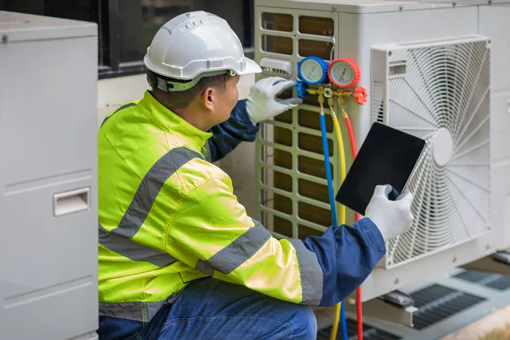 HVAC technician checking refrigerant gauges on a residential air conditioning unit
